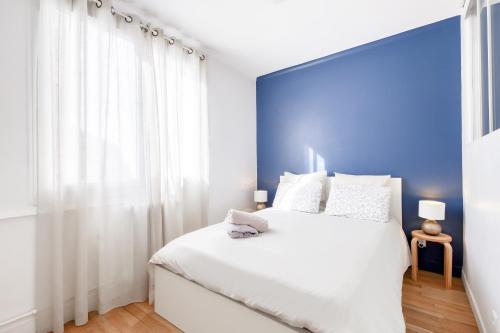 a bedroom with a white bed with a large window at Elegant Central Vincennes Paris in Vincennes