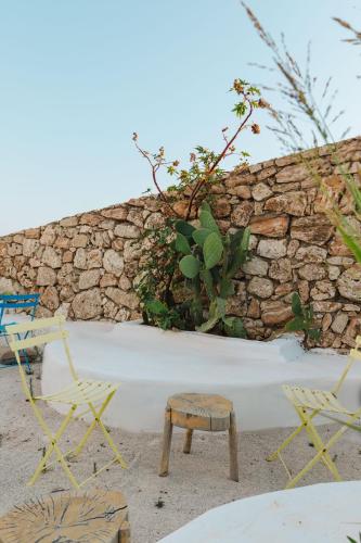 a stone wall with two chairs and a stool at Stone Beach Residence - Adults Only Resort in Qeparo