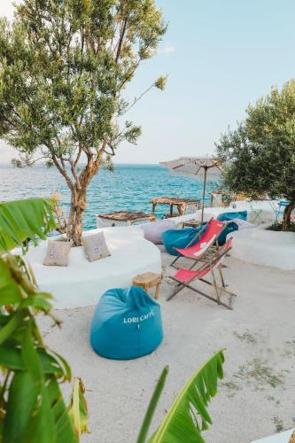 a beach with chairs and a tree and the ocean at Stone Beach Residence - Adults Only Resort in Qeparo