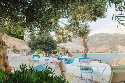 a group of tables and chairs next to the water at Stone Beach Residence - Adults Only Resort in Qeparo