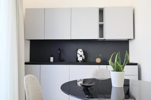 a kitchen with white cabinets and a table with a potted plant at DR Luxury Apartments in Avola