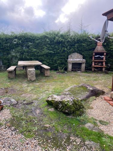 two stone benches and a grill in a yard at Bungalow da Pedreira in Viseu