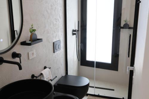 a bathroom with a black toilet and a mirror at DR Luxury Apartments in Avola