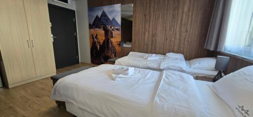 a hotel room with two beds with white sheets at Metropolis Apartamenty Centrum in Kalisz