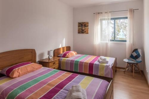 a bedroom with two beds and a chair and a window at SMOOTH T3 APARTMENT in Ponta Delgada