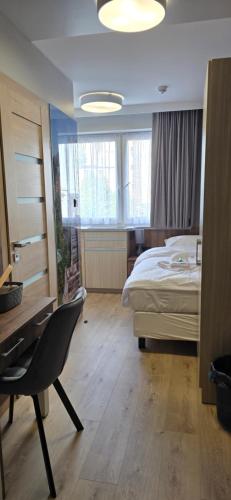 a bedroom with a bed and a desk and a chair at Metropolis Apartamenty Centrum in Kalisz