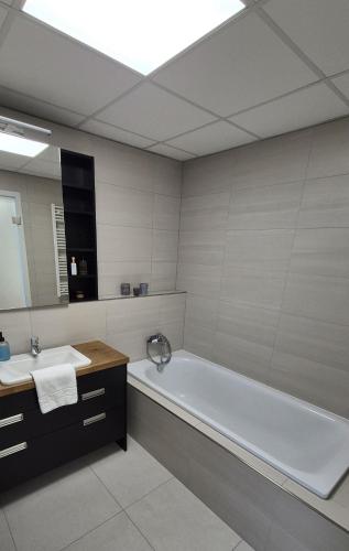 a bathroom with a tub and a sink and a mirror at Hotel Plzeň in Plzeň