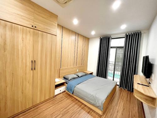 a bedroom with a bed and wooden cabinets and a television at HPT Home II Vinhome Marina chuỗi Apartment - Homestay in Hai Phong