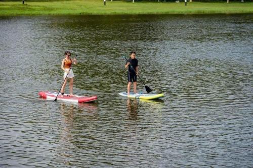two people are standing on paddle boards in the water at Green Villa 5 phòng ngủ ở Flamingo Đại Lải Resort in Phúc Yên