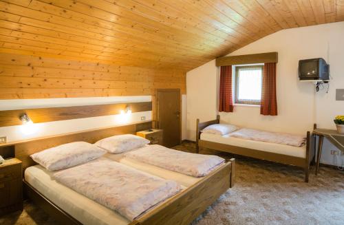 a bedroom with two beds in a wooden cabin at Berghotel Kason in Predoi