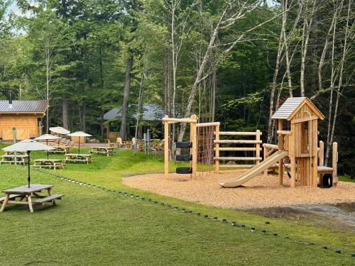 a park with a playground with a slide and benches at Huttopia Les Deux Lacs - Laurentides in Mont-Blanc