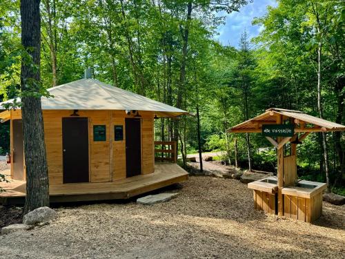 a small wooden cabin in the woods with a sign at Huttopia Les Deux Lacs - Laurentides in Mont-Blanc