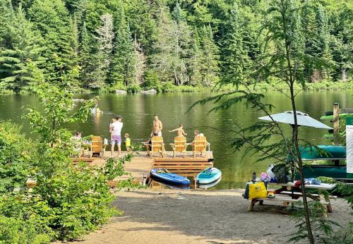 a group of people standing on a dock on a lake at Huttopia Les Deux Lacs - Laurentides in Mont-Blanc