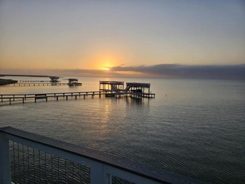 a pier on the water with the sunset in the background at Casa Abide in Galveston