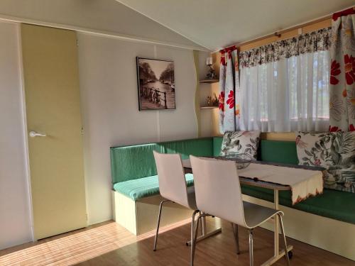 a living room with a green bench and a table and chairs at Chale dos Sobreiros in Bicas