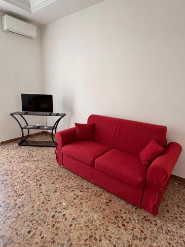 a red couch in a living room with a table at La CASA DEL SOLE in Paceco
