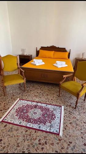 a bedroom with a bed and two chairs and a rug at La CASA DEL SOLE in Paceco