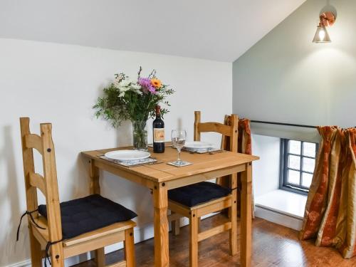 een eettafel met 2 stoelen en een vaas met bloemen bij Fairhead Cottage in Grosmont