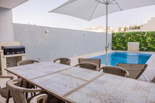 a patio with a table and chairs and a swimming pool at Villa to rent in Gozo- Iż-Żerriegħa tal-Mustarda in Santu Pietru