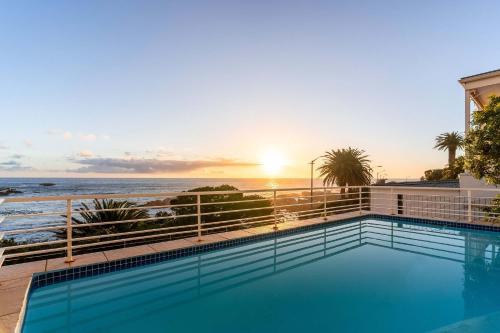 a swimming pool with a view of the ocean at Sunset Azure Studio - Pool Views 2 min to beach in Cape Town