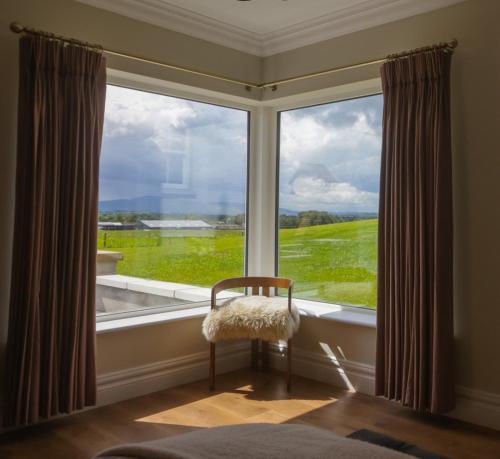 ein Schlafzimmer mit einem großen Fenster mit einem Stuhl vorne in der Unterkunft The Cows Field in Nenagh