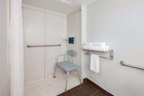 a bathroom with a shower and a blue chair at Four Points by Sheraton College Park Atlanta Airport in Atlanta