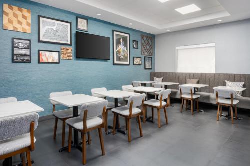 a dining room with tables and chairs and a tv at Four Points by Sheraton College Park Atlanta Airport in Atlanta