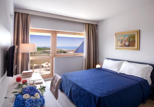 a bedroom with a blue bed and a large window at Grand Hotel Continental in Tirrenia
