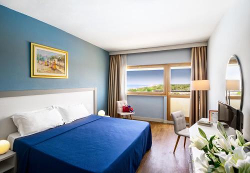 a hotel room with a blue bed and a window at Grand Hotel Continental in Tirrenia