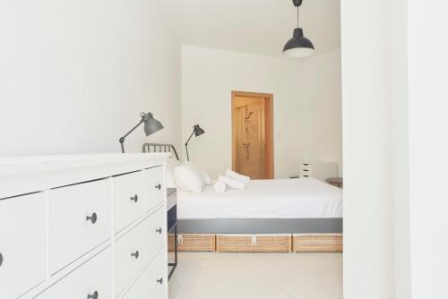 a white bedroom with a bed and a desk at Belleville by Shmoo in San Ġwann