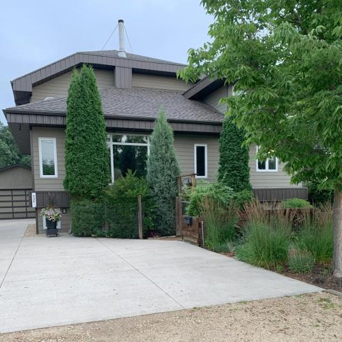 a house with a gate and trees in front of it at Aspen Woodlands Bed and Breakfast in Winnipeg