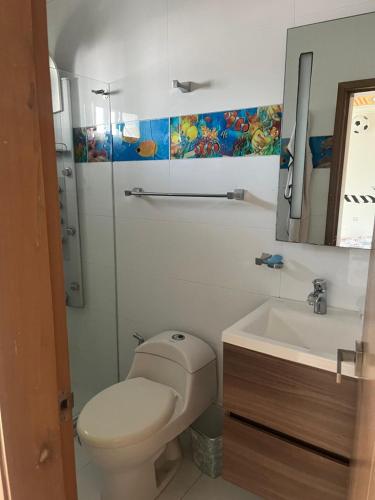 a bathroom with a toilet and a sink and a mirror at Lindo Apartamento suite country club villas in Santa Rosa