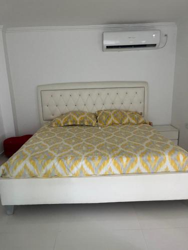 a bed in a bedroom with a white wall at Lindo Apartamento suite country club villas in Santa Rosa