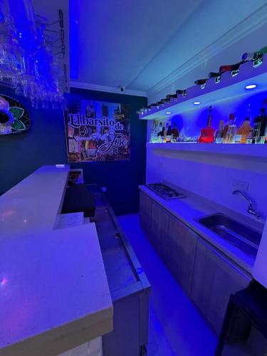 a kitchen with purple lighting and a sink and counters at Lindo Apartamento suite country club villas in Santa Rosa