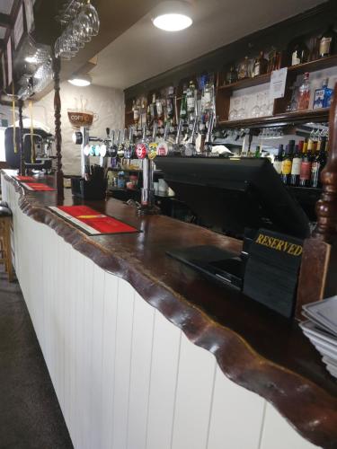 a bar with a wooden counter and a bar with alcohol at The Queens Inn in St Martin Guernsey