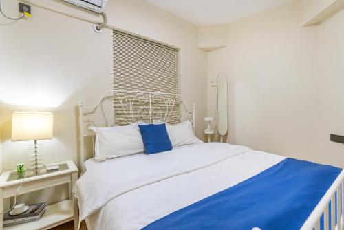 a bedroom with a white bed with blue and white pillows at Misty Nest High Altitude River View B&B Hongyadong Branch in Chongqing