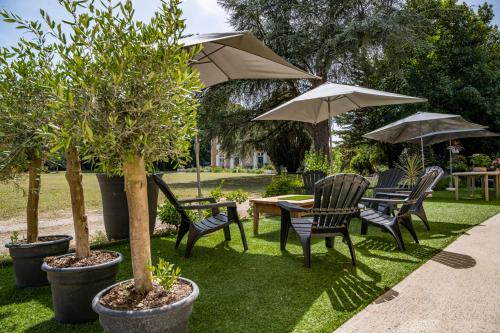 een tafel en stoelen met parasols in de tuin bij Mini gîte cabane in Sainte-Gemme-la-Plaine