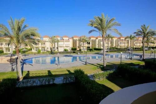 a large swimming pool with palm trees and buildings at Stella villa in Al Wiḩdah