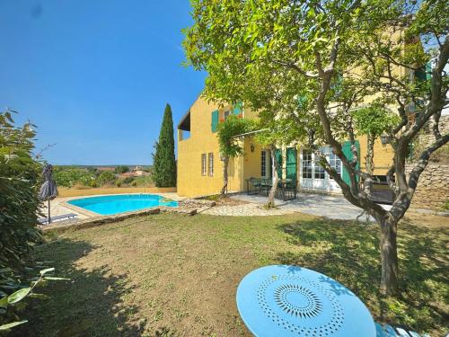 un cortile con una panchina blu di fronte a una casa di Les Hauts de Bezouce, Vue, Piscine & Calme a Bezouce