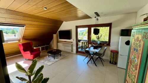 a living room with a red chair and a table at Pension Schmidt - Wipfelblick - Voll ausgestattetes Loft Apartment in Häusern