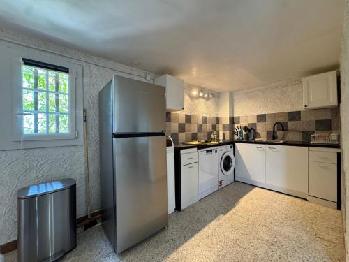a kitchen with a stainless steel refrigerator and white cabinets at Les Hauts de Bezouce, Vue, Piscine & Calme in Bezouce