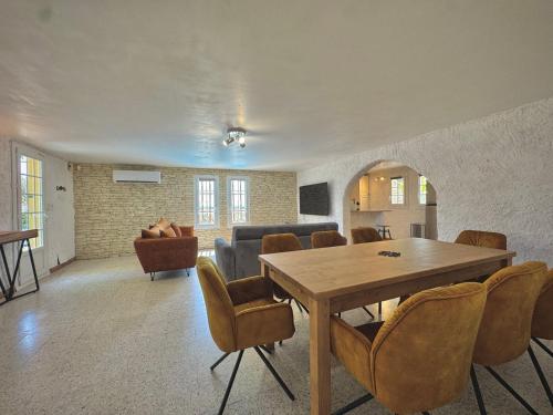 a living room with a wooden table and chairs at Les Hauts de Bezouce, Vue, Piscine & Calme in Bezouce