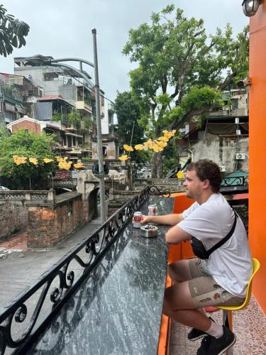 a man sitting on a balcony looking at a river at NT Old Gate Hostel in Hanoi