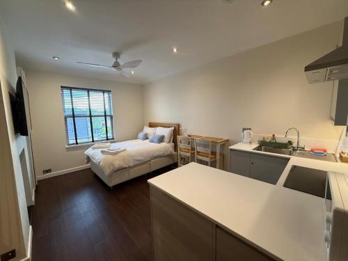 a room with a bed and a kitchen with a sink at Pass the Keys Modern Elegant Studio 20 Minutes to Central London in Twickenham