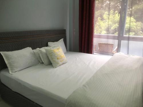 a bed with white sheets and pillows and a window at Bright Serene Studio Bnb in Nairobi