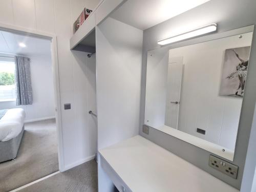 a white bathroom with a mirror and a sink at Cherry Blossom 48 Hot Tub in Garton