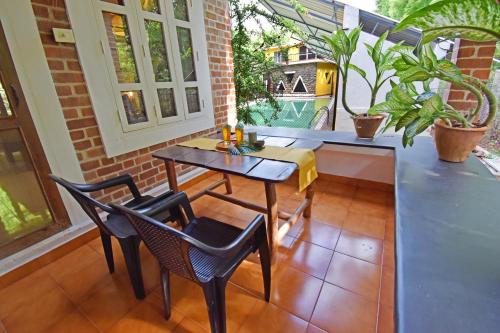 a patio with a table and chairs on a balcony at Inn Pondiville Forest Retreat in Puducherry