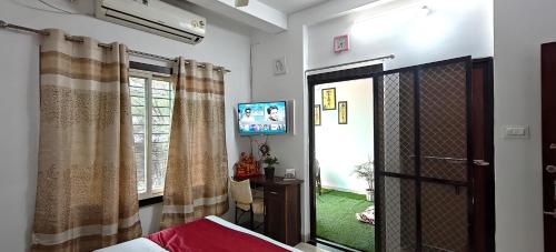 a bedroom with a bed and a tv and a window at Kanakdhara Homestay in Ujjain