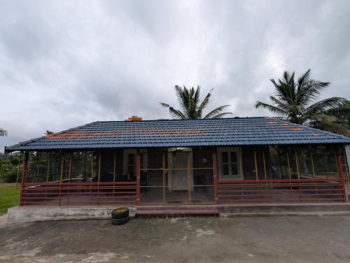 a building with a roof with palm trees in the background at Mountain View Stay in Kushālnagar