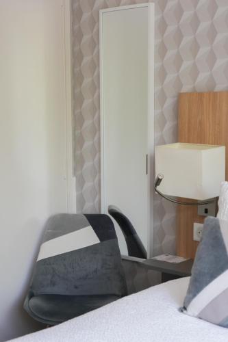a bedroom with a chair next to a bed at Logis Hôtel l'Amandier in Morlaas